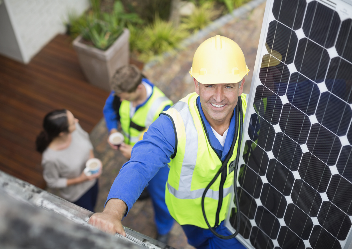 Um instalador de painéis solares sorridente, destacando as vantagens da energia solar residencial.