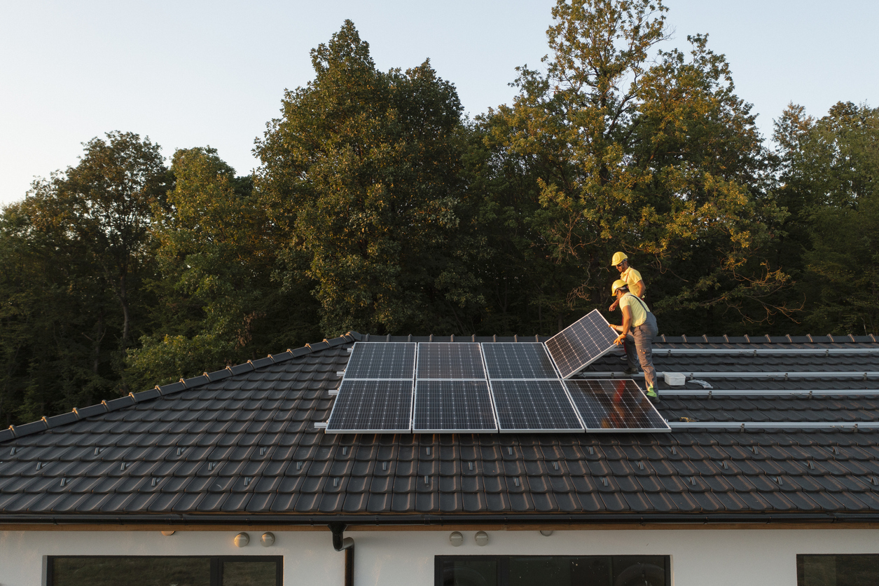 Técnicos instalando energia solar residencial.