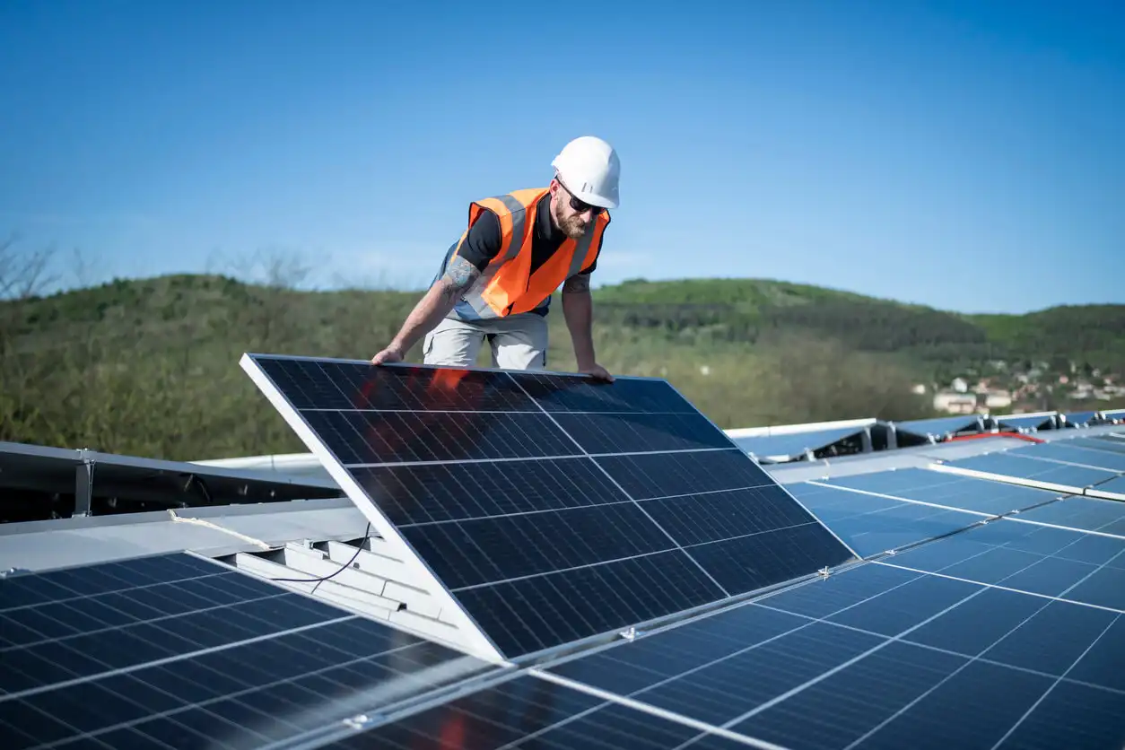 Engenheiro instalando painéis solares em telhado de prédio sustentável ao ar livre, promovendo energia renovável e economia de energia em ambiente externo.