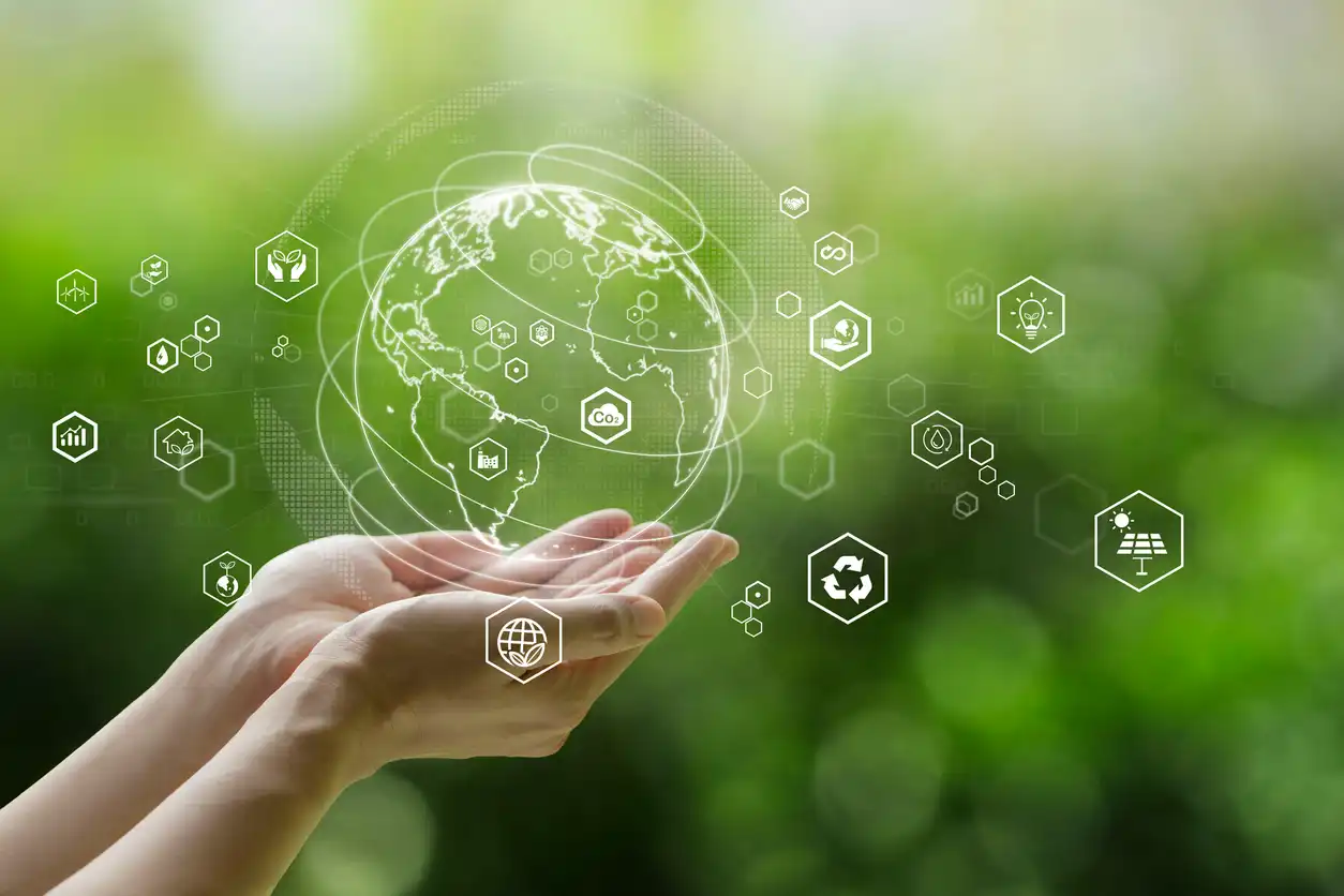 Imagem de uma mão segurando um globo terrestre digital com ícones de sustentabilidade e energia renovável ao redor, representando inovação e cuidado com o meio ambiente.