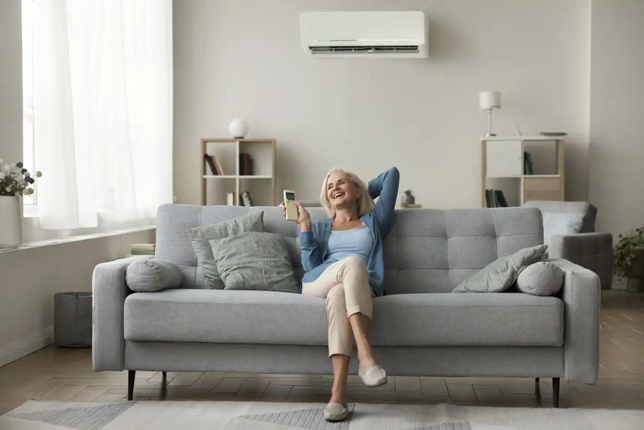 Mulher idosa sorridente relaxando em um sofá confortável na sala de estar moderna, aproveitando um momento de alegria e tranquilidade em casa.