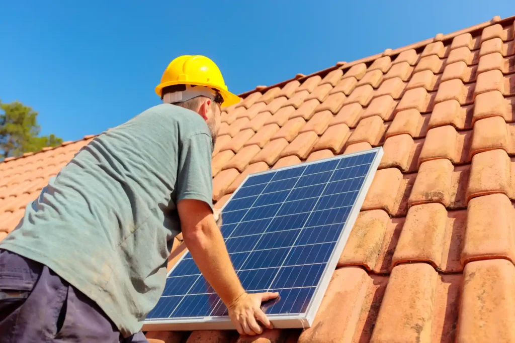 Técnico instalando painel solar em telhado de telhas cerâmicas, promovendo energia solar sustentável e eficiente.