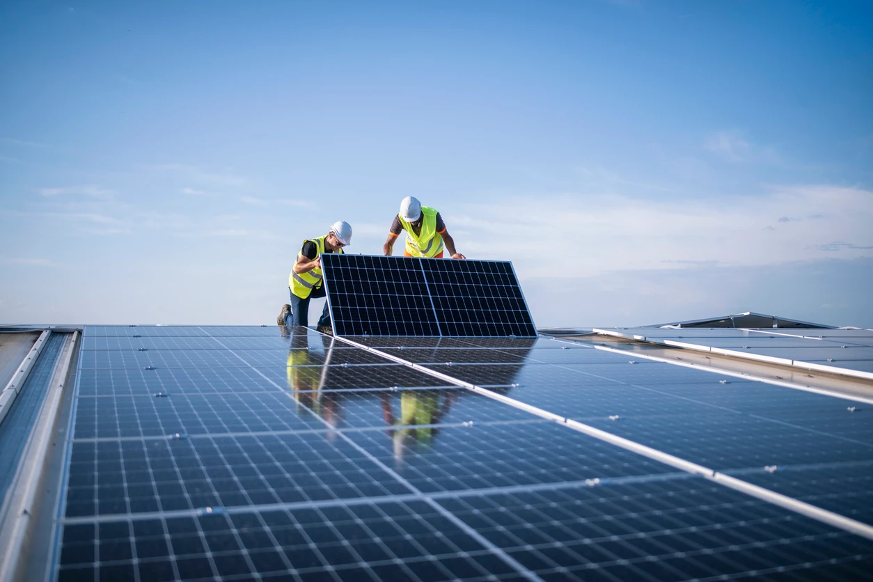 Trabalhadores instalando painéis solares em telhado, promovendo energia solar renovável e sustentável.